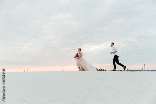 Love Story of a beautiful couple in a pink wedding luxury dress with a bouquet in the Sahara desert, sand, dunes © Олег Блохин