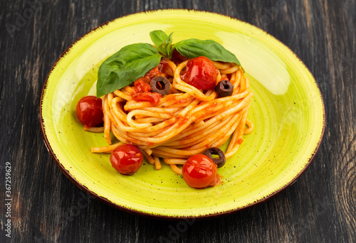Pasta spaghetti Napoli or Napolitana on green plate on black background. Italian cuisine.
