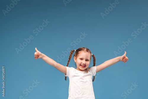 little girl with pigtails in a white t-shirt shows gesture of approval to class