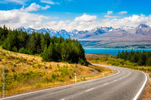 Mount Cook State Highway in New Zealand's South Island is one of the most picturesque alpine roads in the world. Winding road perspective with lake Pukaki and snow-capped mountains in the background. © Daniela Photography