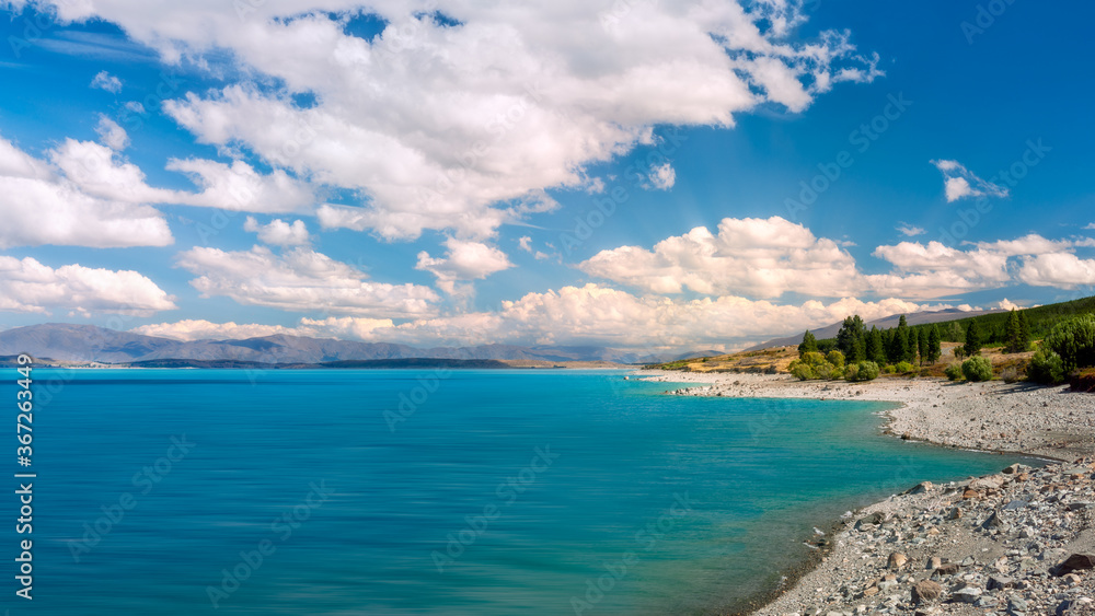 Spectacular alpine panorama with the blue waters of Lake Pukaki in the foreground on a beautiful summer day in Mackenzie Basin in New Zealand's South Island. Spectacular alpine panorama with the blue waters of Lake Pukaki in the foreground on a beautiful summer day in Mackenzie Basin in New Zealand's South Island.