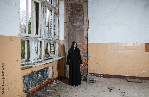young goth woman stands in the room of an abandoned house