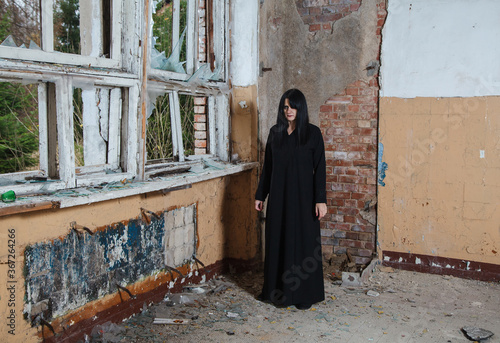 young goth woman stands in the room of an abandoned house © Radnatt