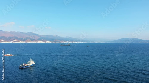 Aerial view of several large and small ships sailing by sea, beautiful mountains on background. Commercial ships in trading port. Transport and logistics services