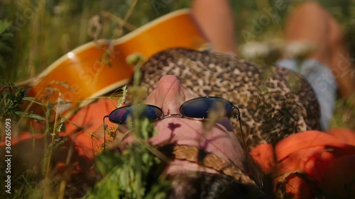 nature, summer vacation, vacation and people concept - happy smiling woman in sunglasses lies on the grass in a summer field. photo