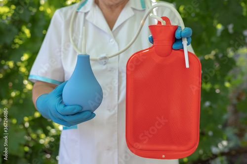 Nurse hold blue enema and red enema bag. Medical Gastrointestinal Colon Background Concept. Intestines cleansing procedure constipation. photo