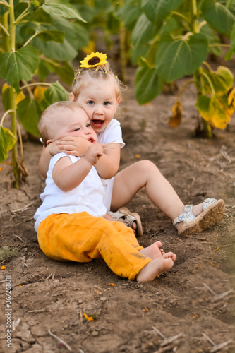 little brother and sister in a field with sunflowers