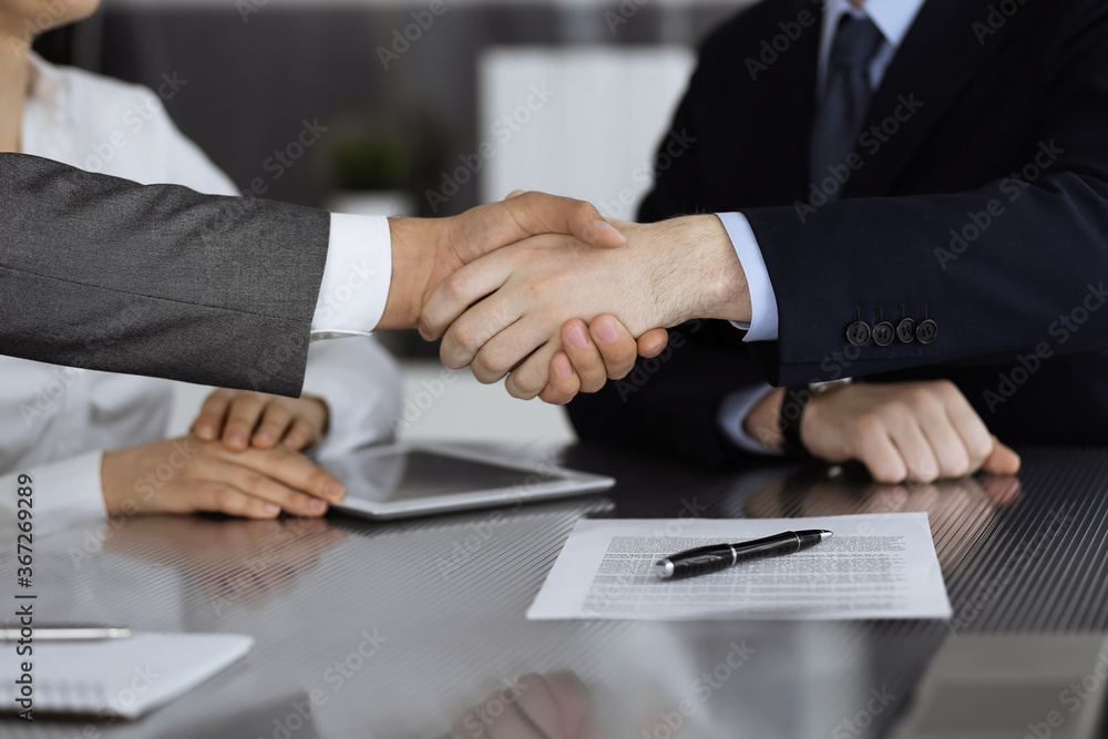 Handshake as successful negotiation ending, close-up. Unknown business people shaking hands after contract signing in modern office Handshake as successful negotiation ending, close-up. Unknown business people shaking hands after contract signing in modern office