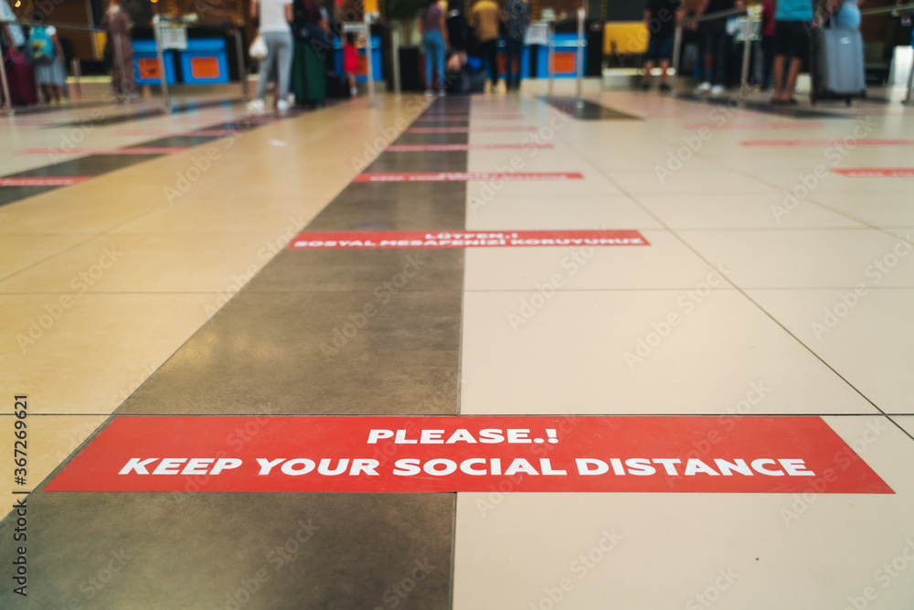 Sticker keep social distance on the floor in the airport check-in lobby, white letters on a red background travel in 2020 - obrazy, fototapety, plakaty 