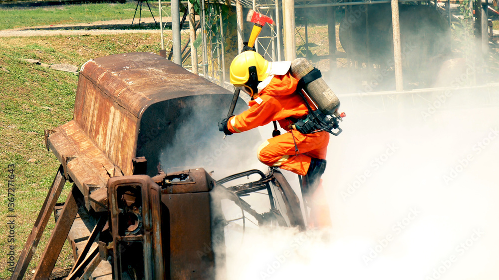 Obraz premium Firefighter fighting with flame using fire hose chemical water foam spray engine. Fireman wear hard hat, body safe suit uniform for protection. Rescue training in fire fighting extinguisher