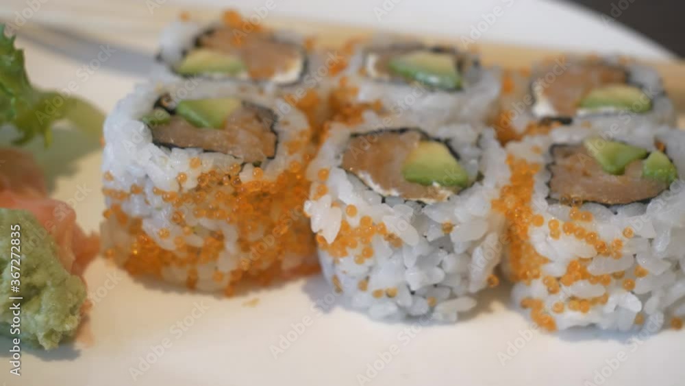 Pieces of sushi rolls covered in caviar served on a plate. Pieces of sushi rolls covered in caviar served on a plate.