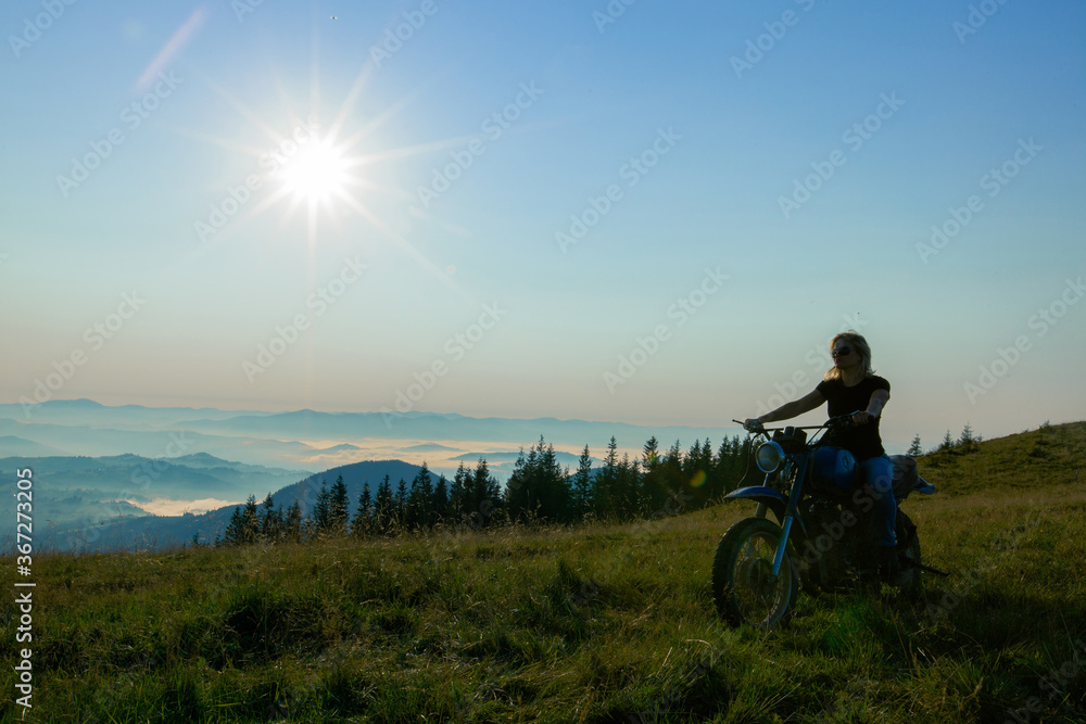 Fototapeta premium girl on a motorcycle travels in the mountains