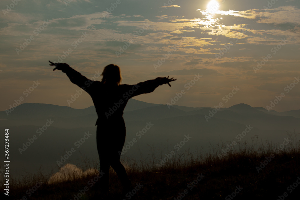 silhouette of a girl on a background of clouds sky in the mountains