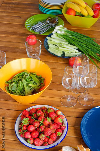 lunch in the country, fresh berries, lettuce, vegetables and green onions on a wooden table. Bright dishes on a wooden table. breakfast in nature