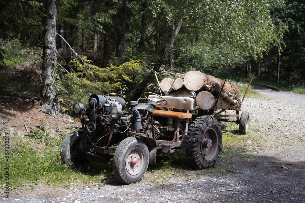 Fototapeta premium Old retro and vintage home-made tractor. Rustic vehicle for lumberjack and woodman work in the wood and forest. 