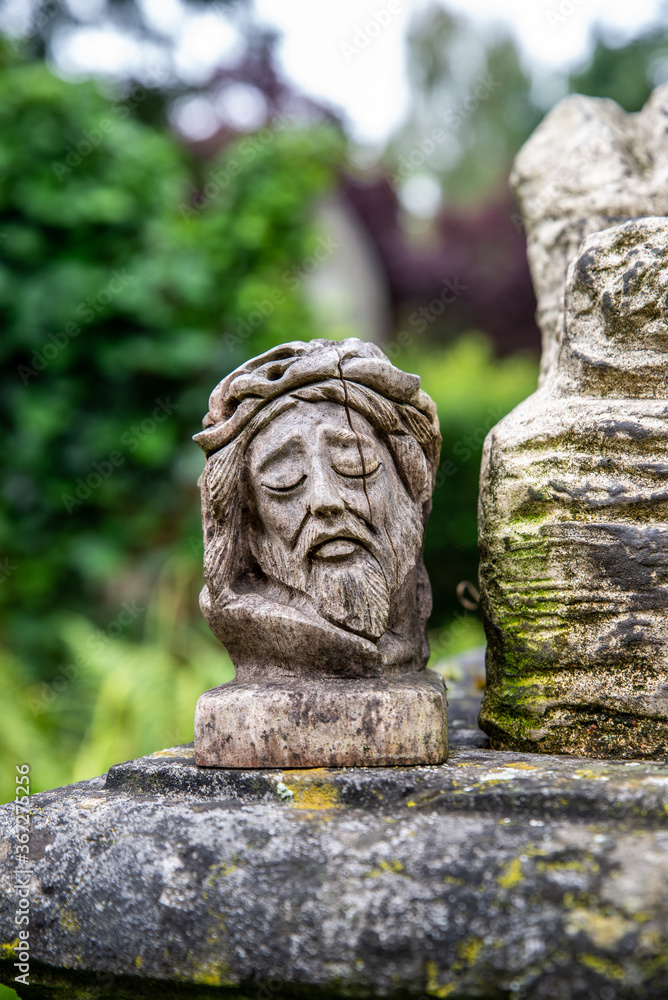 Kleine Jesusfigur aus Holz geschnitzt auf einem Grabstein
