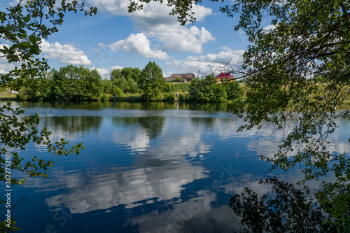 summer  day  nature  landscape  shore  reservoir  lake  water  smooth surface  ripples  reflections  thickets  trees  branches  green  foliage  blue  sky  white  clouds  glare  light  shadow  beauty