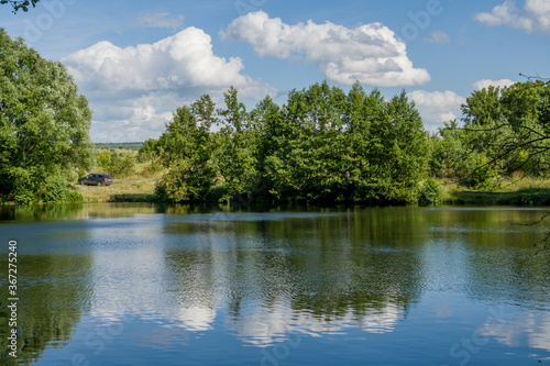 summer  day  nature  landscape  shore  reservoir  lake  water  smooth surface  ripples  reflections  thickets  trees  branches  green  foliage  blue  sky  white  clouds  glare  light  shadow  beauty