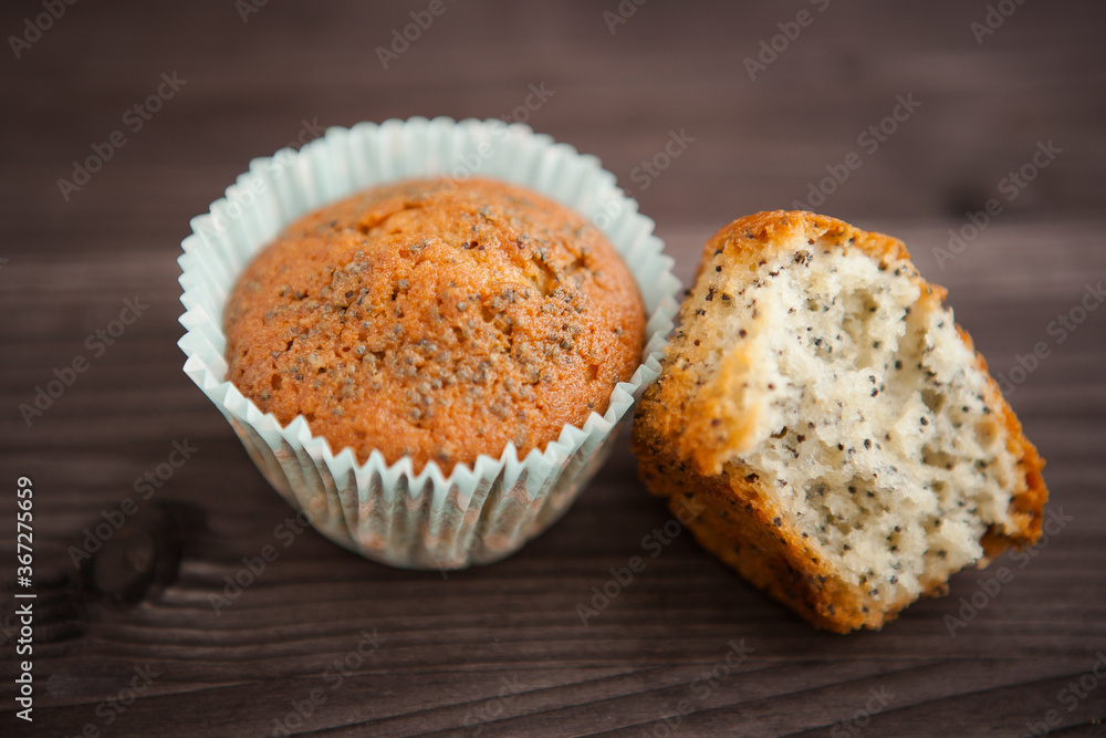 two homemade poppy seed muffins, one broken. on a dark background two homemade poppy seed muffins, one broken. on a dark background