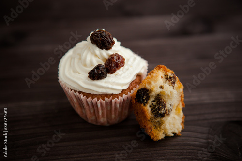 muffin with cream and raisins on a dark wooden background