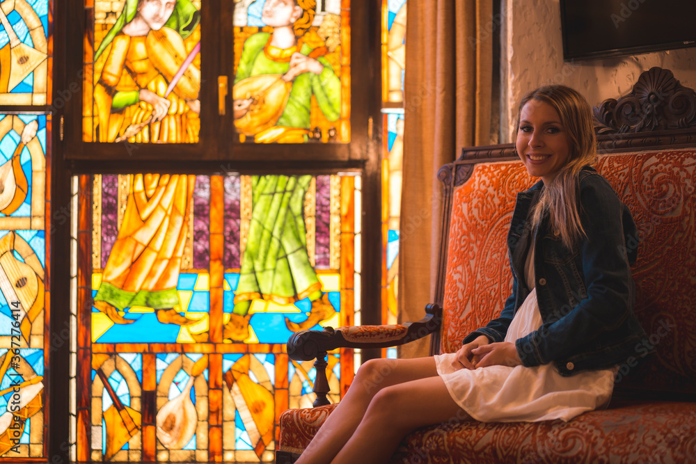 Young blonde caucasian woman in a white dress and denim jacket enjoying a beautiful medieval hotel in the town of Olite in Navarra. Spain, rural lifestyle. Refreshing on the terrace
