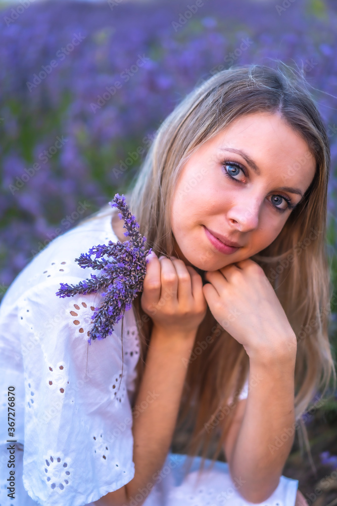 A young blonde Caucasian woman in a white dress in a cultivated lavender field in Navarra, Spain. lifestyle, rural lifestyle. With a bouquet of purple flowers A young blonde Caucasian woman in a white dress in a cultivated lavender field in Navarra, Spain. lifestyle, rural lifestyle. With a bouquet of purple flowers