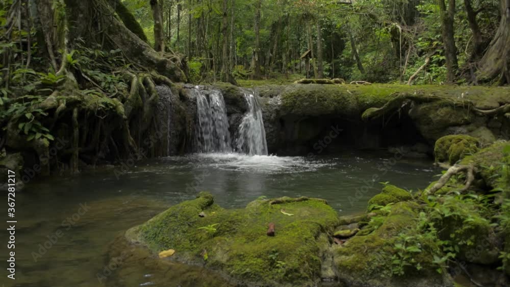 Wonderful scenery of small waterfall that flowing from the jungle through the lush foliage plants into the natural pond. Green freshness in tropical rain forest. Sa Nang Manora forest park. Wonderful scenery of small waterfall that flowing from the jungle through the lush foliage plants into the natural pond. Green freshness in tropical rain forest. Sa Nang Manora forest park.