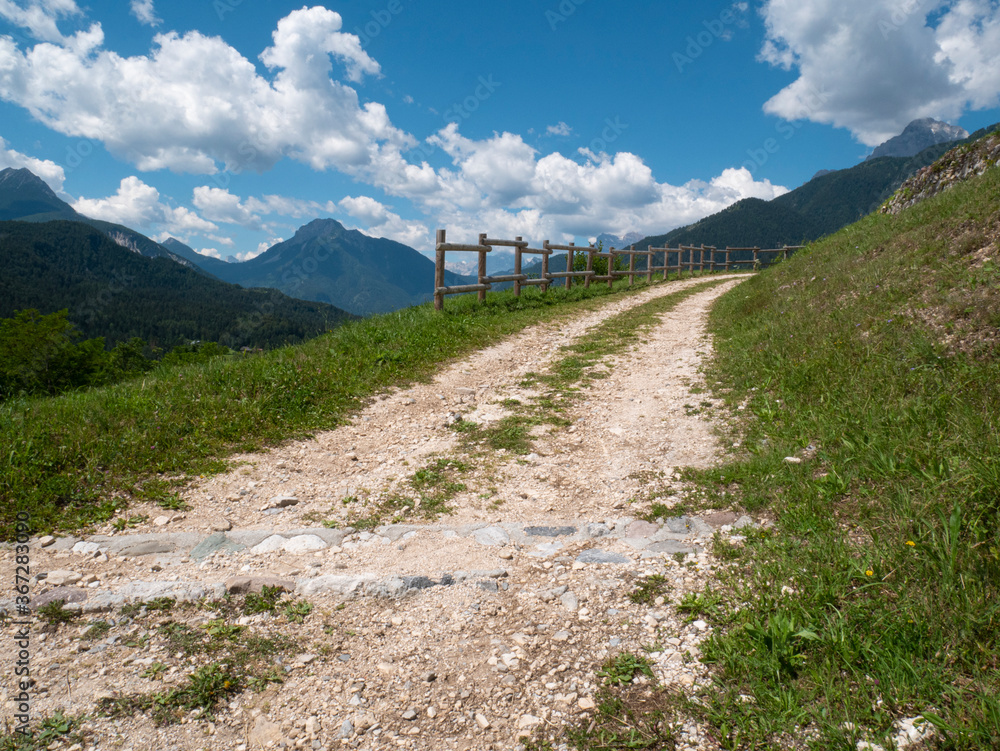 Uphill dirt road in the mountains on the dolomites in the summer road background. Dirt road in the alpine mountains. Pieve di Cadore - Belluno - Italy