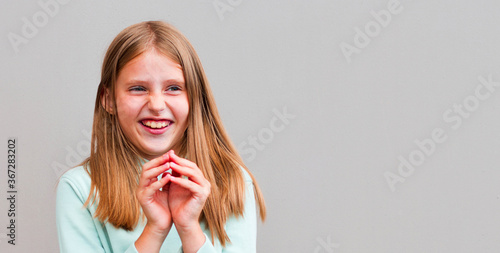 Portrait of sly woman looking with cunning eyes holding her hands together trying to ask something in sly manner. Cute female with hair knot dressed casually expressing her slyness in front of camera