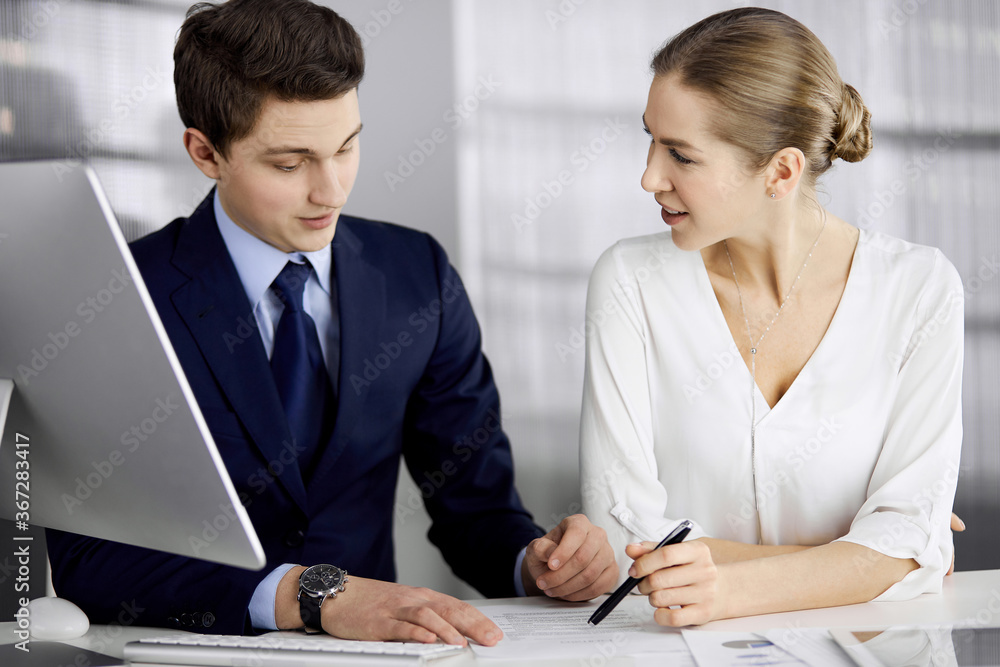 Business people discussing something while sitting in office. Focus at businesswoman while talking to her male colleague. Teamwork and meeting concept Business people discussing something while sitting in office. Focus at businesswoman while talking to her male colleague. Teamwork and meeting concept