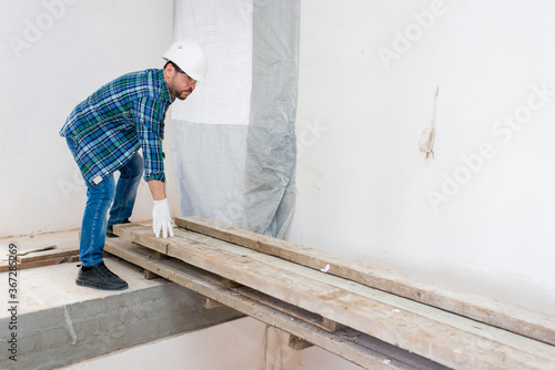 Builder repairer rearranges wooden beams