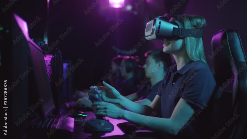 Young blond girl spending time in cybersport club playing games using virtual reality headset and joystick game controller Young blond girl spending time in cybersport club playing games using virtual reality headset and joystick game controller