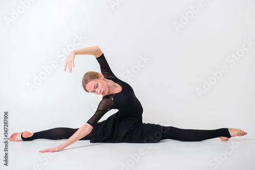 Attractive young female gymnast with pale skintraining calilisthenics exercise on a white studio background