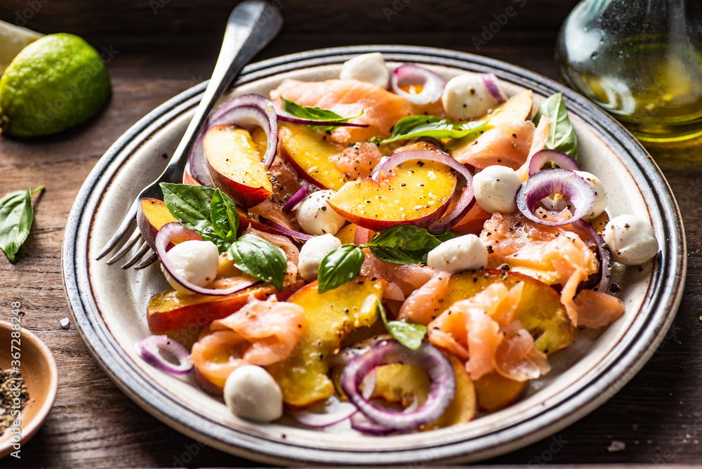 Refreshing summer salad with smoked salmon, peaches, mozzarella, red onion and basil. Wooden background. Refreshing summer salad with smoked salmon, peaches, mozzarella, red onion and basil. Wooden background.
