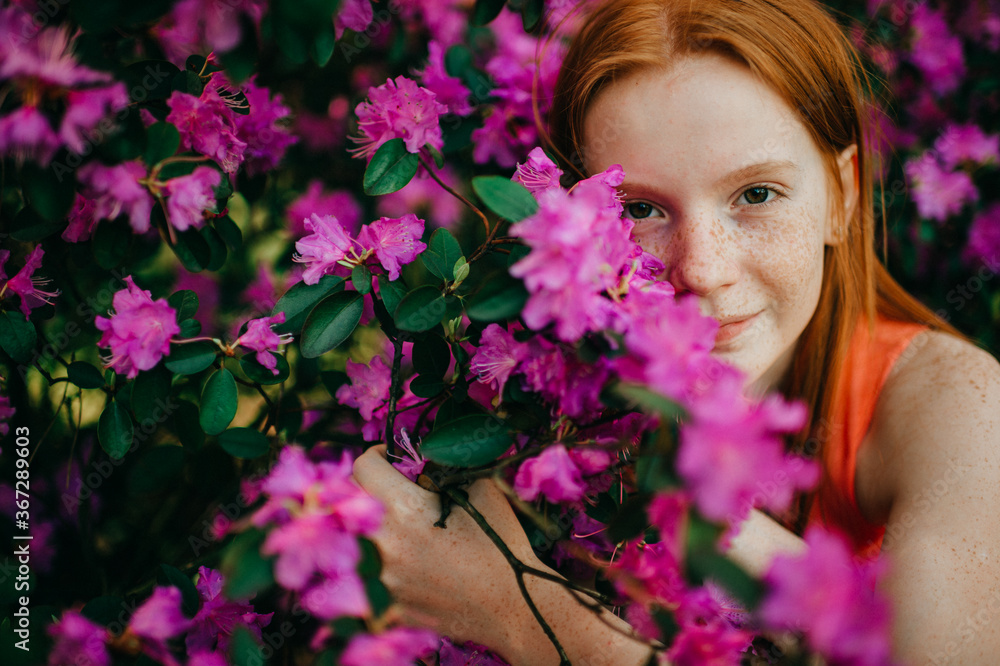 Portrait of attractive young girl in a summer dress enjoys of the purple plants in the botanical garden Portrait of attractive young girl in a summer dress enjoys of the purple plants in the botanical garden
