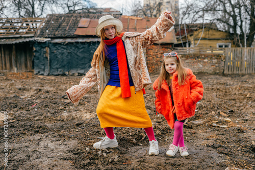 Two cute little sisters in old clothes spend a lot of time together in the village on the autumn holidays