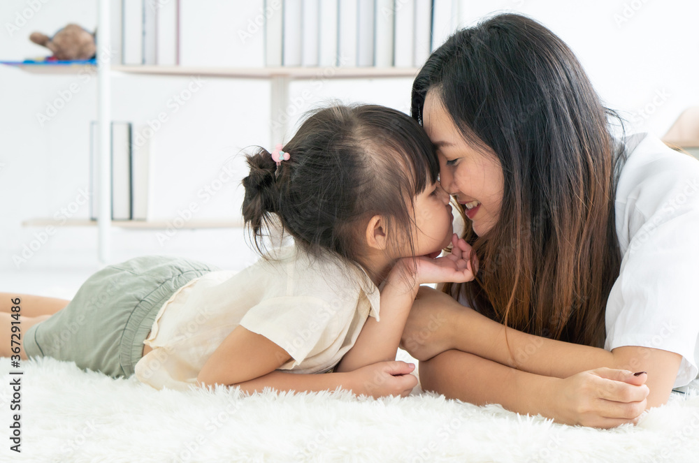 asian mother and young daughter with smiling face are lying on the carpet in the living room at home. family together and relationship concept asian mother and young daughter with smiling face are lying on the carpet in the living room at home. family together and relationship concept