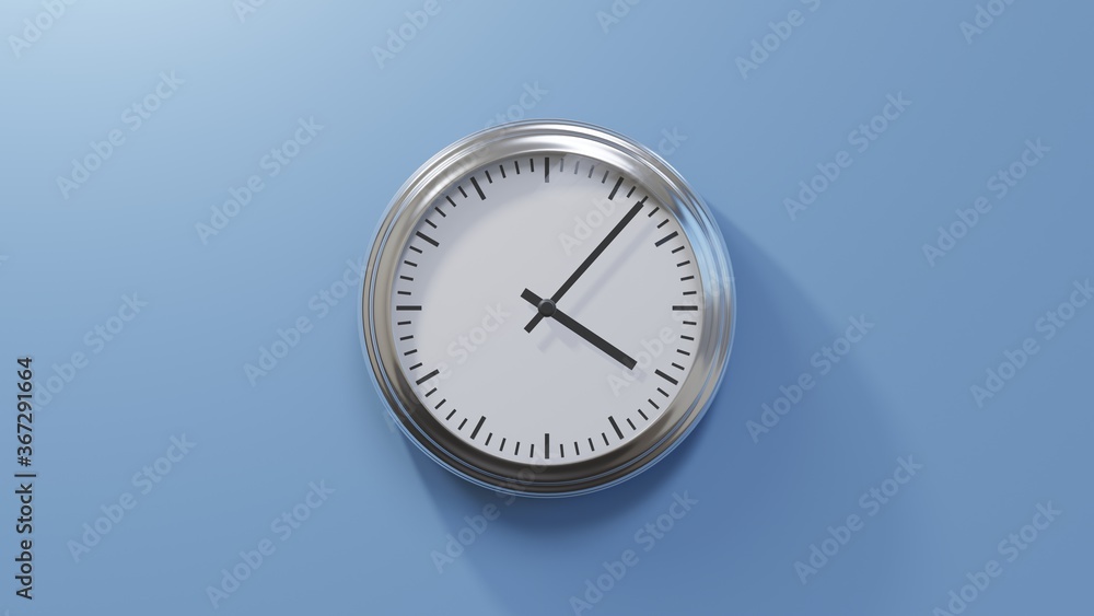 Glossy chrome clock on a blue wall at seven past four. Time is 04:07 or 16:07