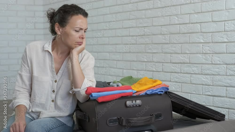 Woman by a suitcase with clothes. The concept of closing borders due to a pandemic. Woman by a suitcase with clothes. The concept of closing borders due to a pandemic.