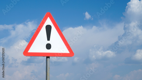 Exclamation mark on road sign background sky with clouds, warning, danger, attention