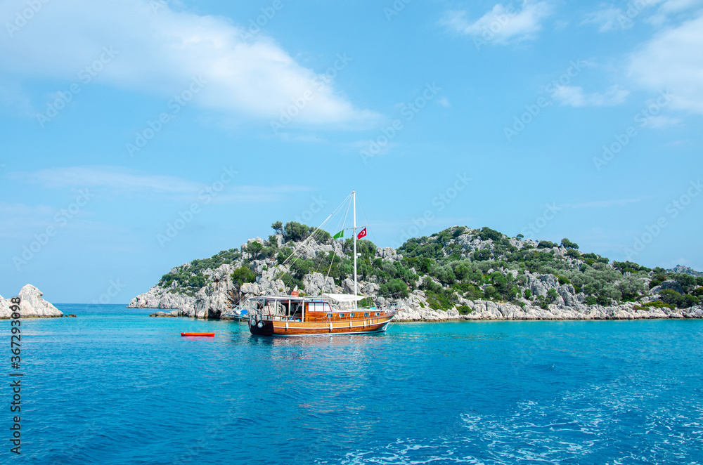 Tourist ship on the background of a beautiful summer mountain landscape on the Mediterranean sea. Excursion to Turkey. Sea tour of the historical monument of architecture. People on vacation