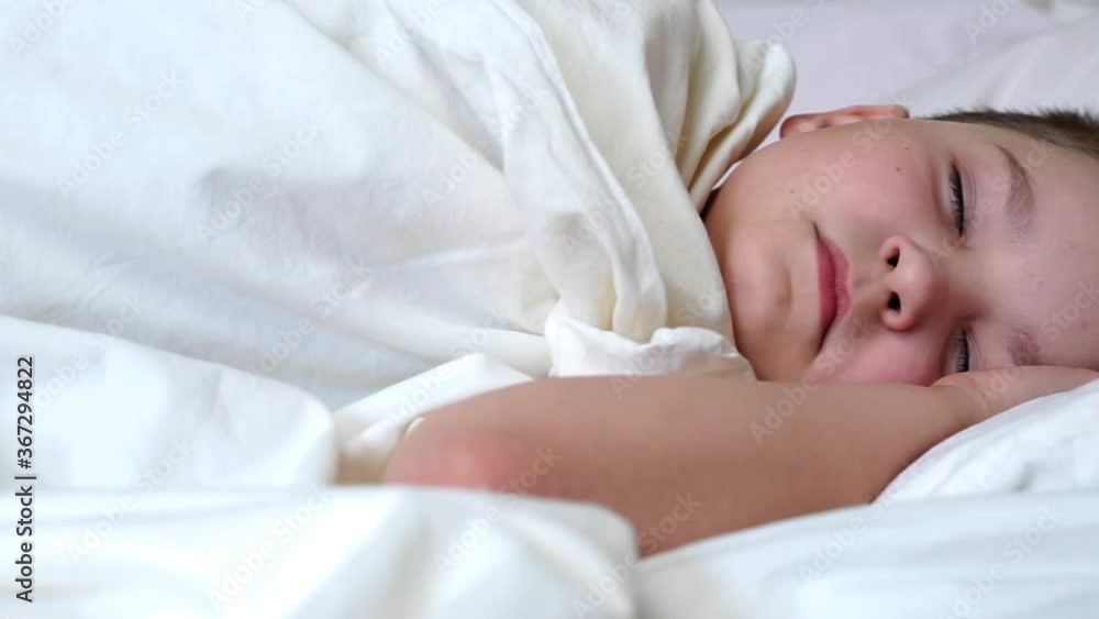 caucasian child boy sleeping in white bed lying on pillow. caucasian young baby kid resting covered with blanket on white sheets in bedroom in morning. dreamy kid sleep with closed eyes. Day sleep caucasian child boy sleeping in white bed lying on pillow. caucasian young baby kid resting covered with blanket on white sheets in bedroom in morning. dreamy kid sleep with closed eyes. Day sleep