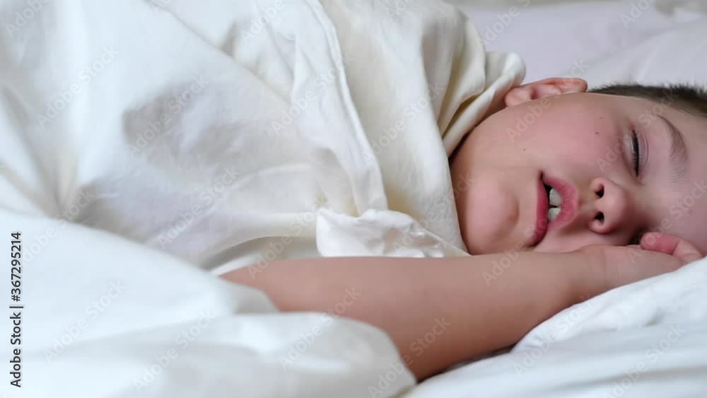 little child boy sleeping in white bed lying on soft pillow. caucasian young baby kid relaxing covered with blanket on white sheets in bedroom in morning. kid has a nightmare dream little child boy sleeping in white bed lying on soft pillow. caucasian young baby kid relaxing covered with blanket on white sheets in bedroom in morning. kid has a nightmare dream