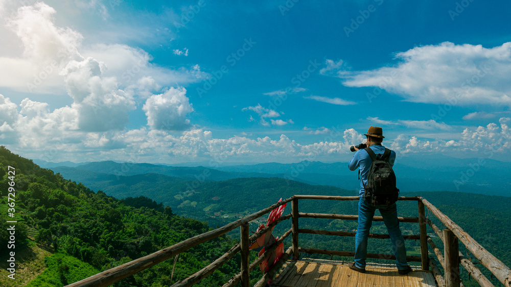 Young male tourists taking pictures of the scenery on the bridge at Mon Jam, Chiang Mai, Thailand