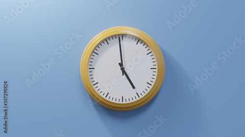 Glossy orange clock on a blue wall at fifty-nine past four. Time is 04:59 or 16:59