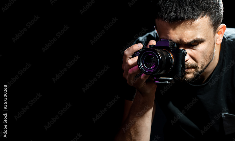 The person is holding a camera and is set up for shooting. The photographer looks into the camera's viewfinder and takes pictures. Object on a black background. The person is holding a camera and is set up for shooting. The photographer looks into the camera's viewfinder and takes pictures. Object on a black background.
