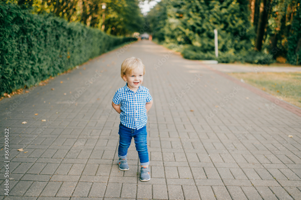 Picture of little caucasian boy in blue summer clothes walks to the park in summer Picture of little caucasian boy in blue summer clothes walks to the park in summer