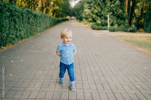 Picture of little caucasian boy in blue summer clothes walks to the park in summer © benevolente
