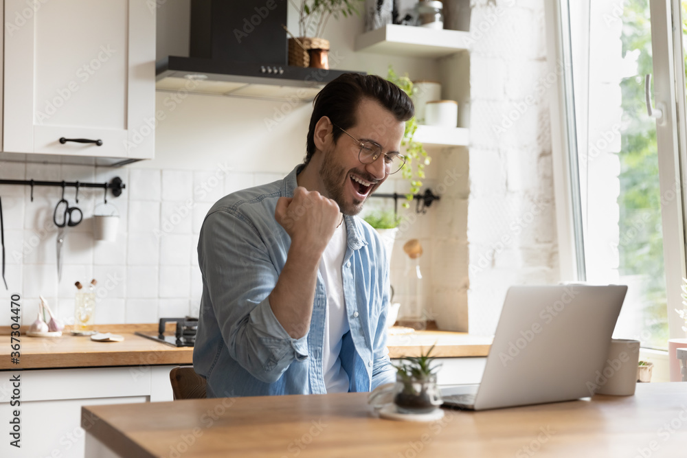 Overjoyed millennial Caucasian guy in glasses look at laptop screen triumph read good news or email on gadget, excited young man feel euphoric win online lottery on computer, luck, success concept Overjoyed millennial Caucasian guy in glasses look at laptop screen triumph read good news or email on gadget, excited young man feel euphoric win online lottery on computer, luck, success concept
