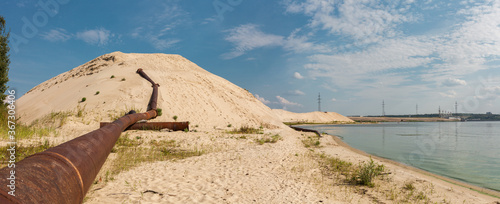 Dredger dredging with sand washing on beaches. Special dredging tube for sand to create new land. Sand washing on sea beaches. Dredging, washing out sand on beach during construction sea terminal